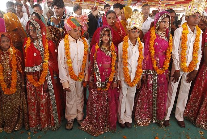  Boys and girls from the Saraniya community wearing garlands pose for pictures after their engagement ceremony at Vadia village