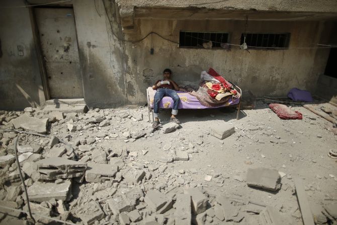 A wounded Palestinian sits against a residential building where he lives, which police said was destroyed in an Israeli air strike, in Gaza City