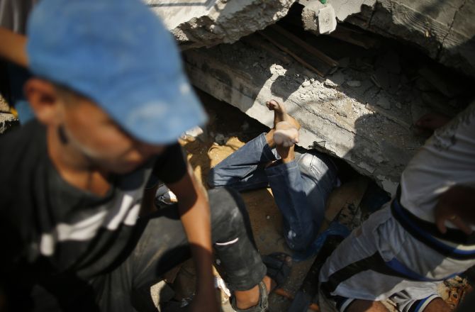 Palestinians search for belongings under the rubble of a residential building, which police said was destroyed in an Israeli air strike, in Gaza City