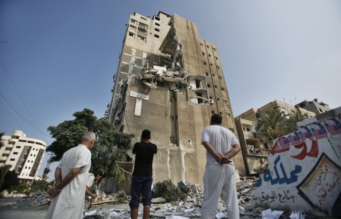 Palestinians look at a residential building which police said was hit in an Israeli air strike