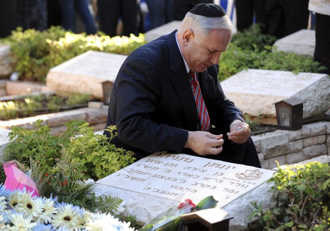 Israel's Prime Minister Benjamin Netanyahu lights a candle by his brother Yonatan's grave during a memorial ceremony for him at Mount Herzl military cemetery in Jerusalem 