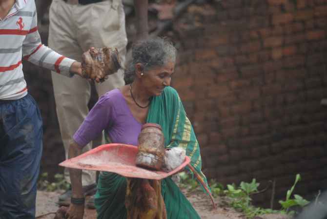 A woman, whose house was destroyed in the landslide, picks up her belongings