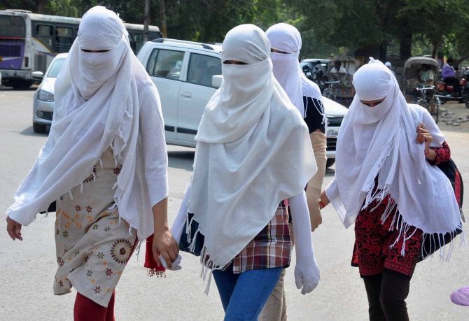 Women walking to college use their dupattas as a means to protect themselves. No rain and the harsh sun has made the weather unbearable in Allahabad.