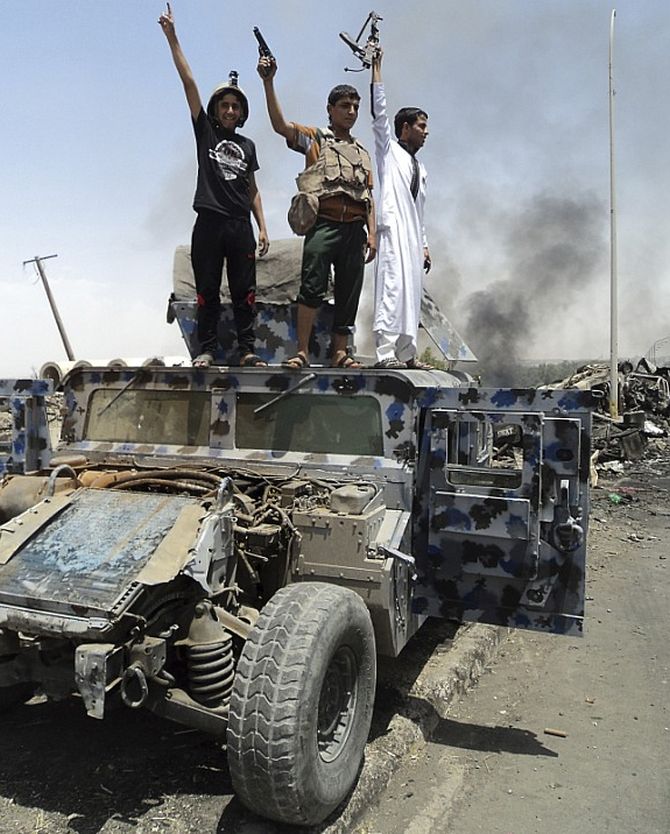 ISIS militants stand atop a car after they overtook Mosul.