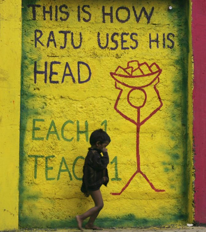 A child walks past graffiti on a street side wall in Mumbai.