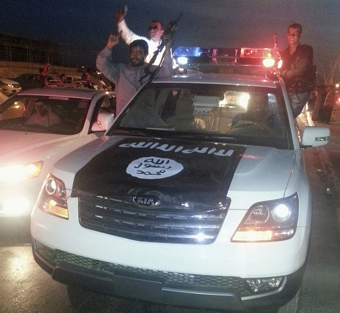 Fighters of the Islamic State of Iraq and the Levant celebrate on a police vehicle along a street in the city of Mosul, Iraq
