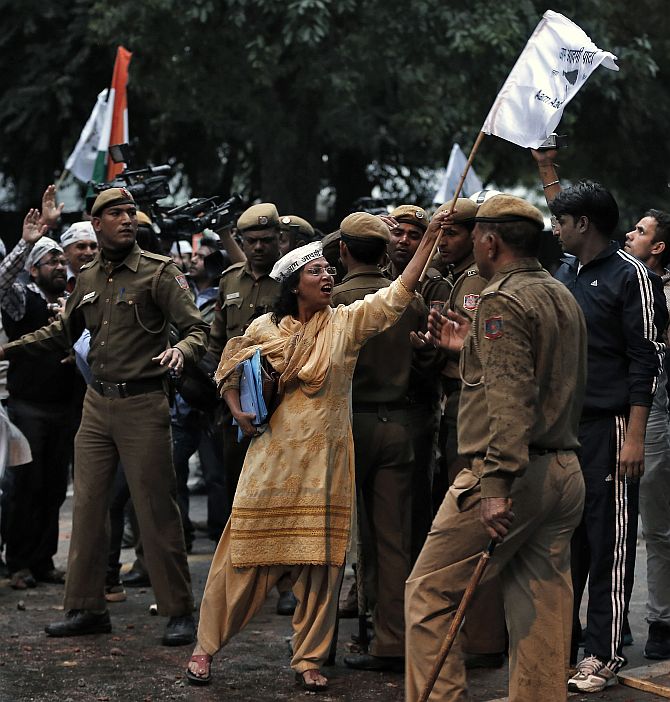 An AAP supporter shouts slogans as she shows a flag towards policemen during a protest outside the BJP headquarters