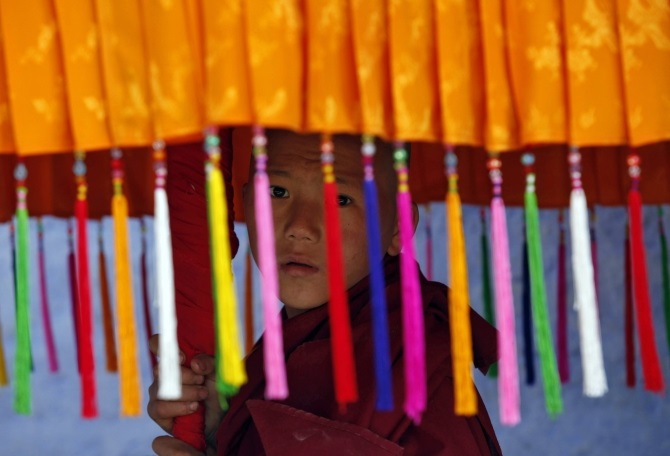 A young monk holds a traditional parasol as he waits for the arrival of the Dalai Lama in Pemayangtse monastery in Pelling, Sikkim