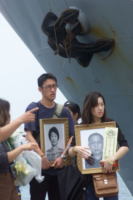 Relatives hold photos of loved ones who were aboard China Airlines flight CI 611 which crashed into the sea on Saturday prepare to board a Taiwan navy transportation ship, to make their way to a traditional spirit-calling ceremony near the island of Penghu.