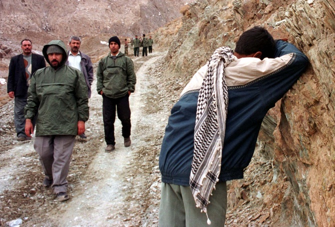 A Revolutionary Guard grieves over his dead c-orescue workers look on, on a near Kerman, in southeastern Iran.