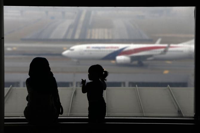 A woman and a girl look at a Malaysia Airlines plane on the tarmac of Kuala Lumpur International Airport