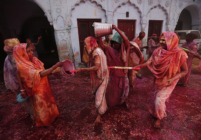 Widows spray coloured water on each other during Holi celebrations