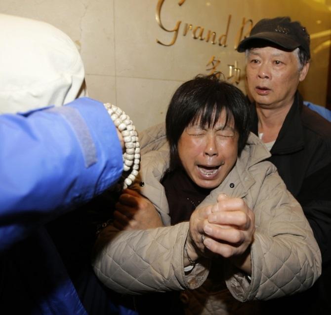 A family member of a passenger aboard Malaysia Airlines flight MH370 cries after watching a television broadcast of a news conference, at the Lido hotel in Beijing