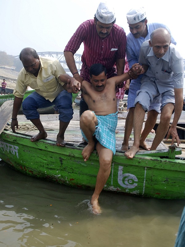 Arvind Kejriwal is helped by his party supporters as he prepares to take a dip in the waters of the Ganga after he arrived to attend a public rally ahead of the general elections in Varanasi
