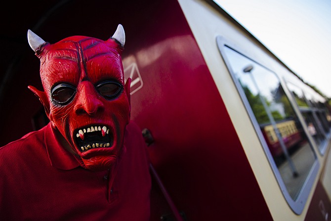 A man with devil make-up poses for a picture on a HSB light railway carriage travelling through the Harz mountains during celebrations marking the Walpurgisnacht pagan tradition