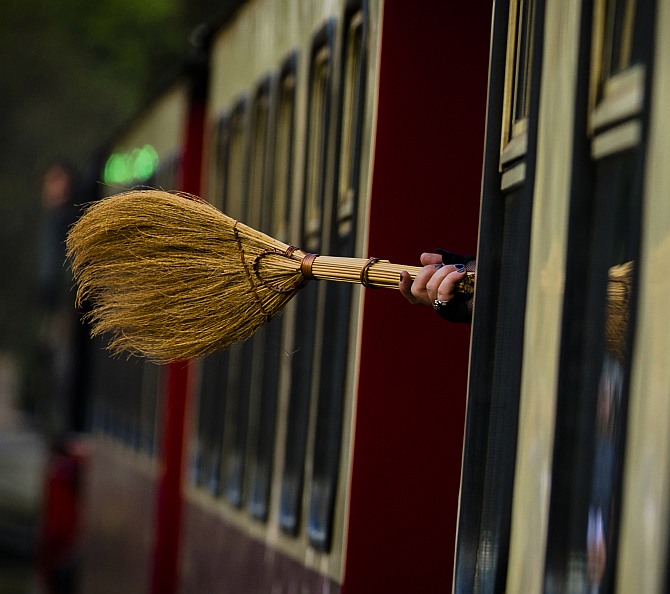 A woman holds a broom as she travels on the HSB light railway through the Harz mountains celebrating the Walpurgisnacht pagan festival