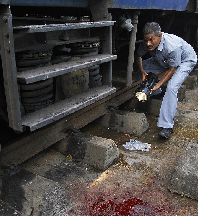 A member of the bomb disposal squad examines the area next to a passenger train on which two explosions occurred, at the Chennai railway station.