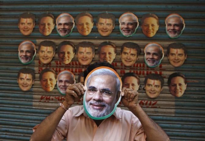 A Modi supporter covers his face with a Modi mask.