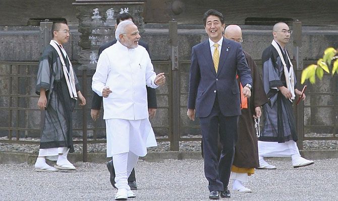 Prime Minister Narendra Modi and his Japanese counterpart Shinzo Abe smile with Buddhist monks in the background, during their visit to Toji Buddhist temple