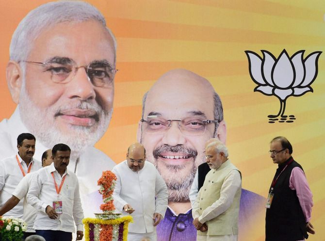 BJP President Amit A Shah lights the lamp as Prime Minister Narendra D Modi  and Finance Minister Arun Jaitley look on at the inauguration of the party's national executive meeting in Bengaluru, April 8, 2015. Photograph: Shailendra Bhojak/PTI