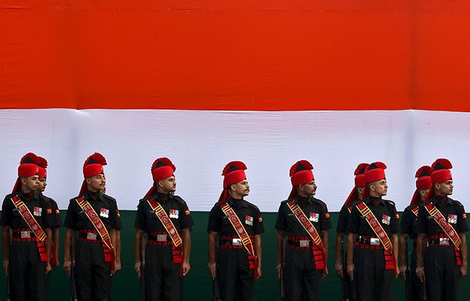Indian soldiers stand guard in front of an India's national flag