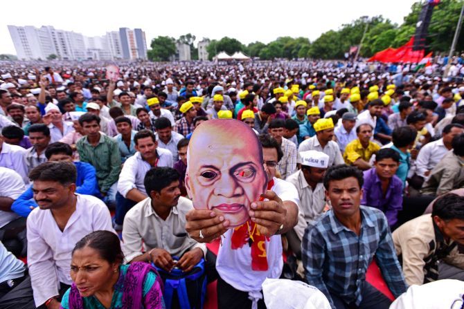 A youth displays a mask of Sardar Vallabhbhai Patel during the Kranti rally (revolution march) organised by the Patel ( Patidar) community to press their demands for reservation, at the GMDC Ground in Ahmedabad. Photograph: PTI Photo