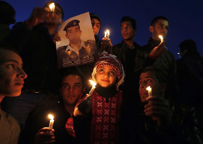 Jordanians hold up a poster of pilot Muath al-Kasaesbeh who was executed by IS