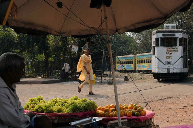 A Tram passes by a fruit vender in Kolkata 