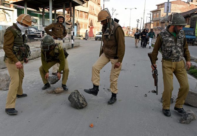 Security personnel remove a boulder from a deserted street after protests following the alleged molestation of a girl by a jawan. Photograph: S Irfan/PTI