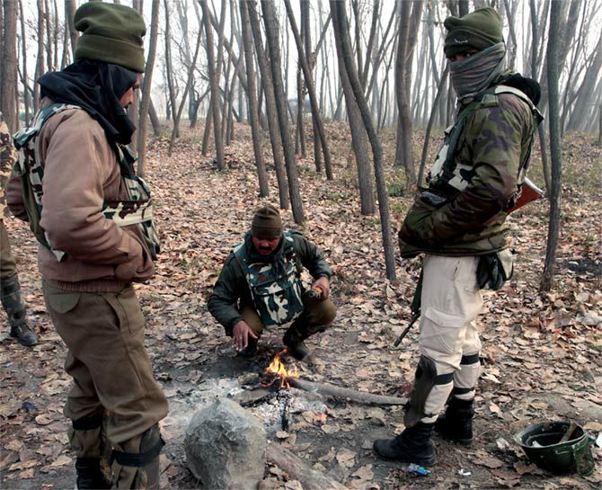 CRPF troopers try to keep warm near a fire