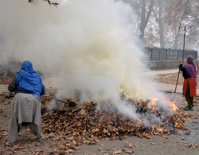 Women burn dry chinar leaves to make charcoal for fires to keep warm