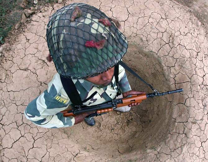 BSF soldier stands guard in a trench near Jammu