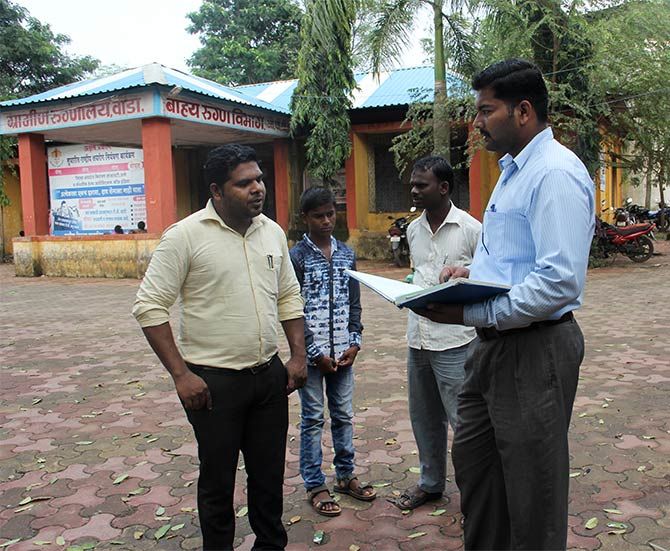Dr Samadhan Pagare (in yellow shirt) consulting with a patient's relative from Vikramgadh outside his room. The patient, a boy, in the background, was suffering from a disorder of the cerebellum that made him lose his balance, with his father listen intently. Earlier, this boy was diagnosed by Dr Pradip Jadhav inside his cabin at RH, Wada.