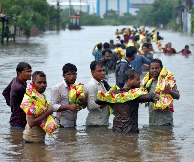 People carry packets of snacks handed out by volunteers in a flooded neighbourhood after heavy rains in Ahmedabad, July 2017. Photograph: Amit Dave/Reuters