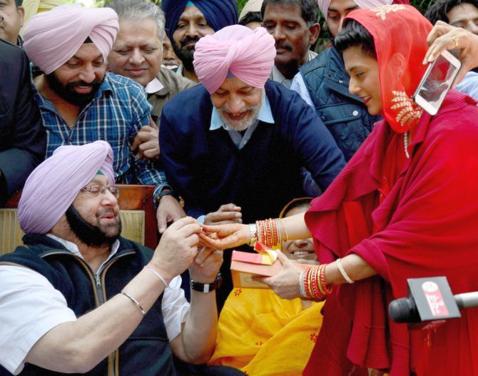 Captain Amarinder Singh is offered sweets by his grand daughter-in-law Mriganka Singh after his election victory. Photograph: PTI Photo