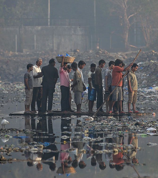 Residents use an improvised raft to cross a sewage canal in a slum in Mumbai, February 11, 2015. Residents pay Rs 2 per trip. Photo: Danish Siddiqui/Reuters