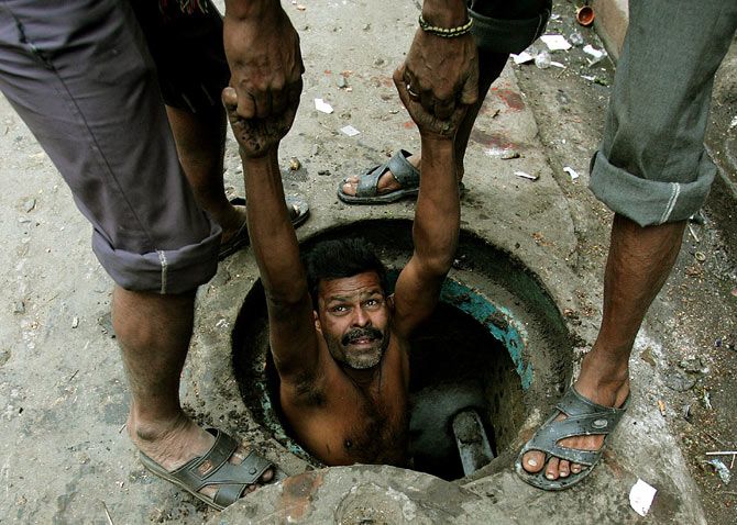 A labourer is lowered to clean a sewage hole in Kolkata, December 16, 2005. Photo: Parth Sanyal/Reuters
