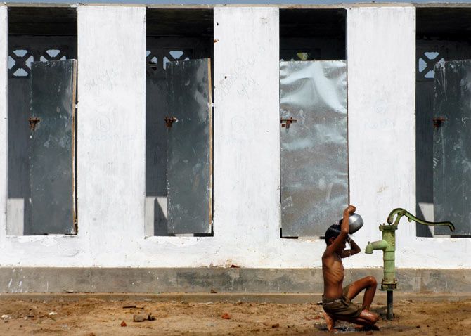 A boy takes bath outside newly-built toilets in a village on the outskirts of Nagapattinam, Tamil Nadu, December 24, 2005. Photo: Jagadeesh NV/Reuters