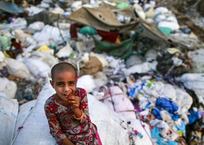 A girl sits on a sack of discarded clothes at a slum in Mumbai, India, April 20, 2016. Photo: Danish Siddiqui/Reuters