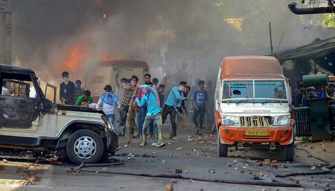 During the Bharat Bandh, April 2, 2018, protesters hurl brickbats as smoke billows out of burning cars in Muzzaffarnagar, Uttar Pradesh. Photograph: PTI Photo