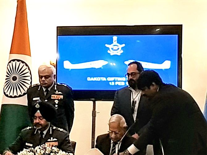 Air Commodore M K Chandrasekhar (retd) and Air Chief Marshal Birender Singh Dhanoa sign the gift deed as Air Marshal Shirish Baban Deo, the vice chief of the air staff, left, and Rajeev Chandrasekhar look on