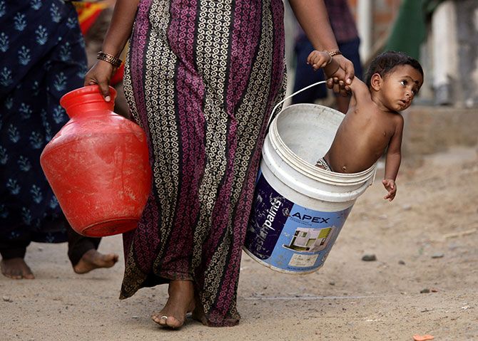 A woman carries her son in a bucket after collecting water from a municipal water tanker on the outskirts of Chennai. Photograph: P Ravikumar/Reuters.