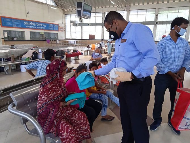 Varanasi Junction Station Director Anand Mohan and his staff provide clothes to passengers who have been marooned at the Varanasi railway station for more than a month