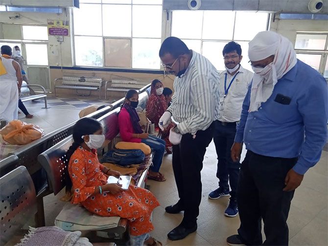 Varanasi Junction Station Director Anand Mohan (in striped shirt) and his staff provide a notebook and pens to a child passenger who has been marooned at the Varanasi railway station for more than a month