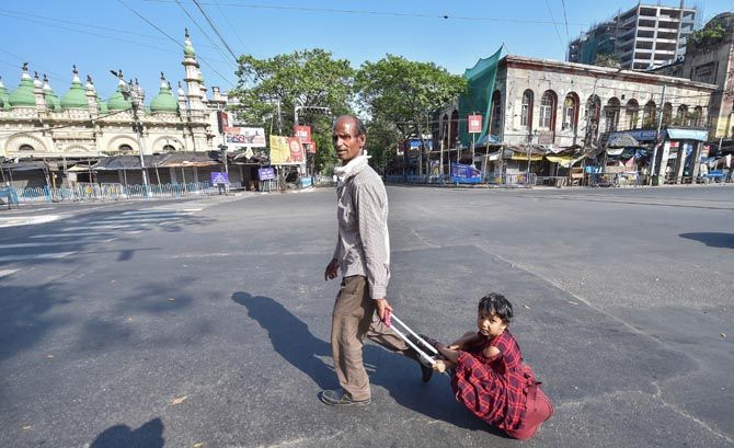 An Indian carries his daughter on a trolley bag in Kolkata after he could not find transport to return to his village during the nationwide lockdown, March 27, 2020. Photograph: Swapan Mahapatra/PTI Photo