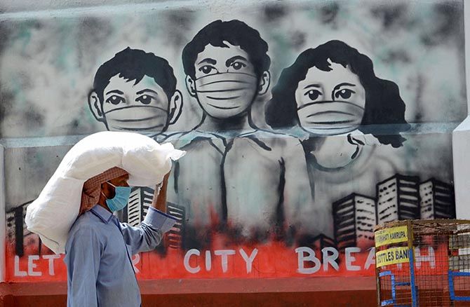 A labourer in Guwahati walks past a mural during the nationwide lockdown