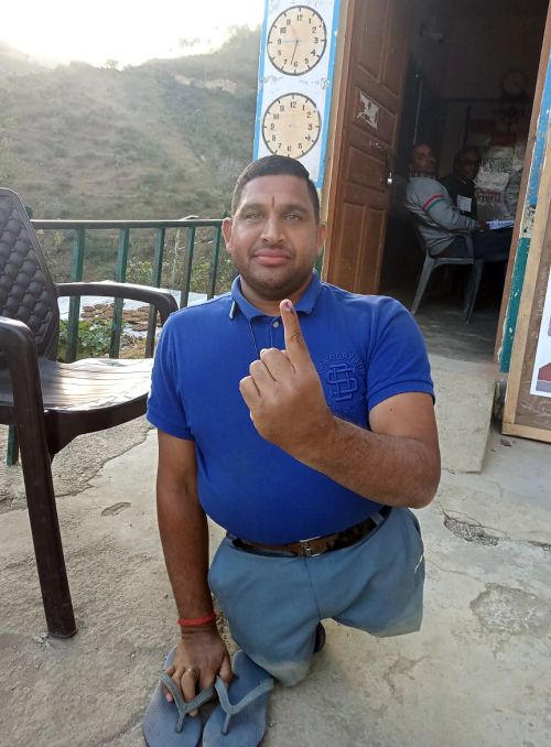 A specially-baled voter shows his ink-marked finger in Solan