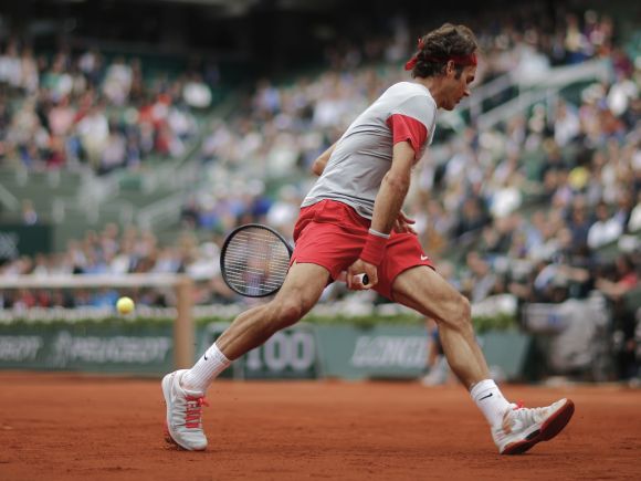 Roger Federer of Switzerland returns the ball to Ernests Gulbis of Latvia