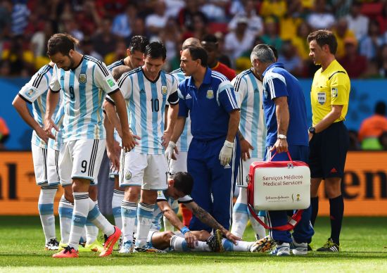 Angel di Maria of Argentina receives treatment as his teammates look on 