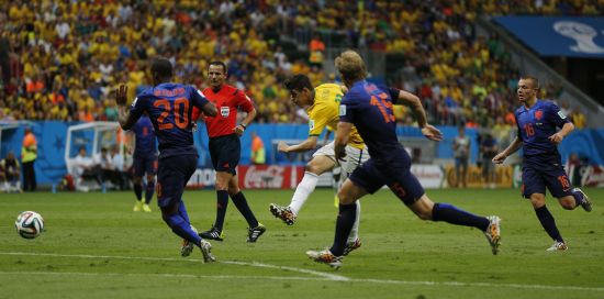 Brazil's Oscar (C) attempts a shot against the Netherlands 